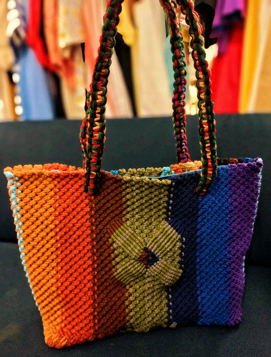 Colorful woven bag with a pattern against a blurred background of clothing.